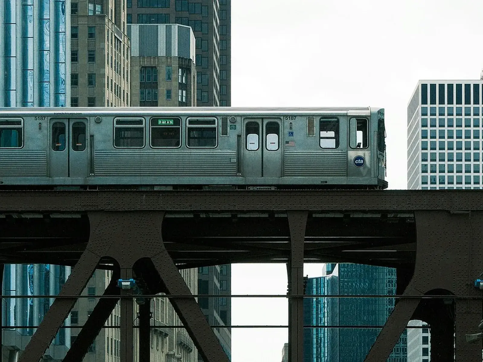A metro train running on an elevated viaduct between city buildings