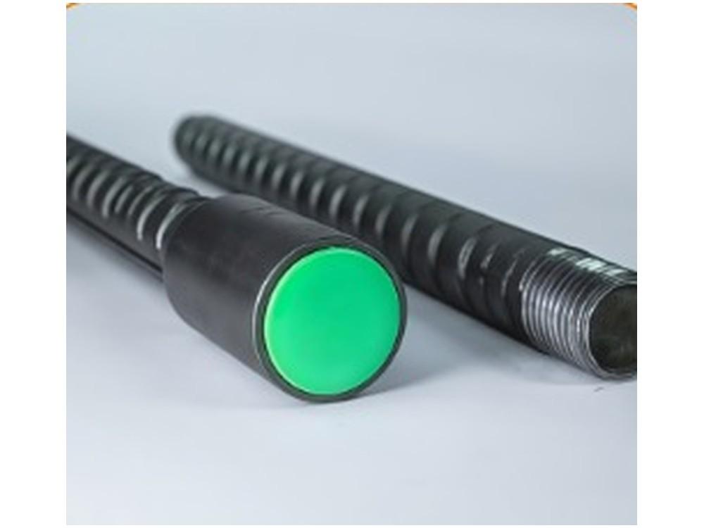 A green protection cap pushed onto a threaded bar end beside an uncapped bar